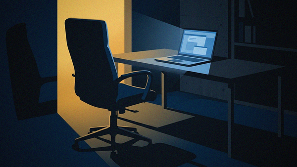 A dimly lit room showcasing a desk with a laptop and a chair, emphasizing a quiet work environment.